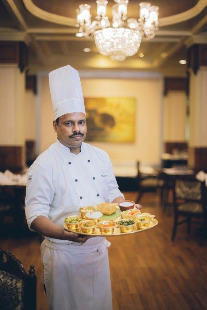 Taj Ganges Варанаси Экстерьер фото A chef with a selection of Indian snacks